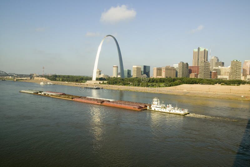 Daytime view of tug boat pushing barge down Mississippi River in front of Gateway Arch and skyline of St. Louis, Missouri as seen royalty free stock images