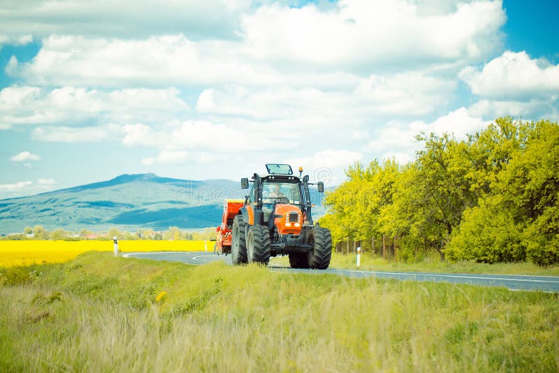 De aandrijving van de landbouwbedrijftractor op weg stock fotografie De aandrijving van de landbouwbedrijftractor op weg stock fotografie
