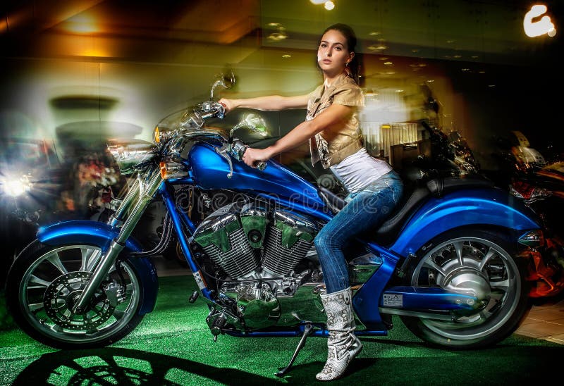 De aantrekkelijke meisjeszitting op een blauwe motorfiets, moto toont stock foto De aantrekkelijke meisjeszitting op een blauwe motorfiets, moto toont stock foto