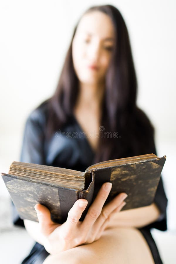 De aantrekkelijke vrouw kleedde zich in zwarte sexy nachtkleding die op bed in de ochtend leggen en boek lezen stock afbeeldingen De aantrekkelijke vrouw kleedde zich in zwarte sexy nachtkleding die op bed in de ochtend leggen en boek lezen stock afbeeldingen