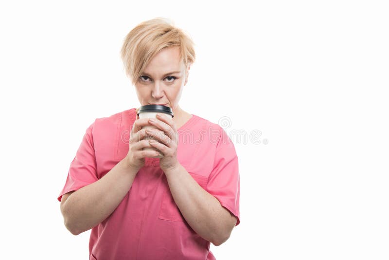 De aantrekkelijke vrouwelijke verpleegster die roze dragen schrobt holdings meeneemcof stock foto De aantrekkelijke vrouwelijke verpleegster die roze dragen schrobt holdings meeneemcof stock foto