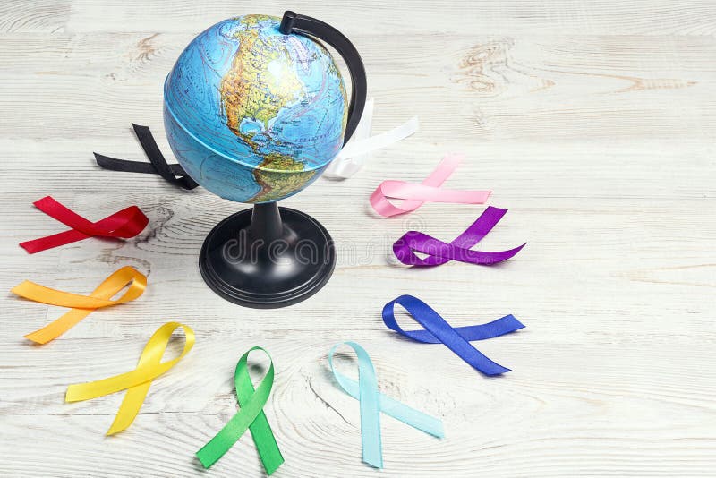 De aarde met een cirkel van kleurrijke bewustmakingslinten op houten tafel Wereldkankerdag concept, 4 februari