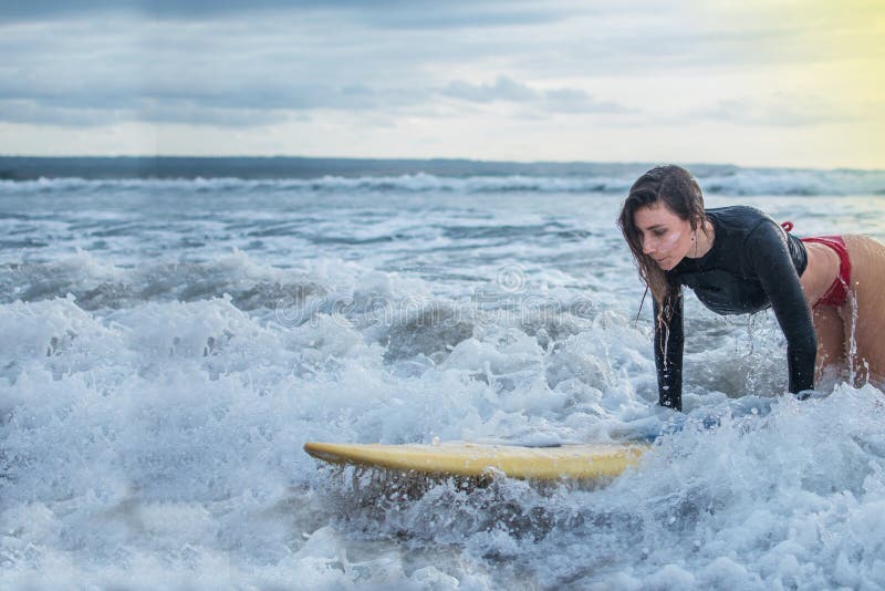 De actie van jonge vrouw probeert aan stap die zich op de surfplank in med van de oceaan bevinden, die op de de vaardigheid van g royalty-vrije stock fotografie De actie van jonge vrouw probeert aan stap die zich op de surfplank in med van de oceaan bevinden, die op de de vaardigheid van g royalty-vrije stock fotografie