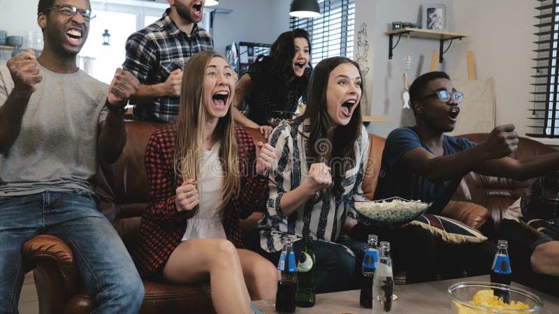 De Afrikaanse Amerikaanse sportenfans vieren thuis winst De hartstochtelijke verdedigers schreeuwen het letten op spel op TV 4k l stock foto's De Afrikaanse Amerikaanse sportenfans vieren thuis winst De hartstochtelijke verdedigers schreeuwen het letten op spel op TV 4k l stock foto's