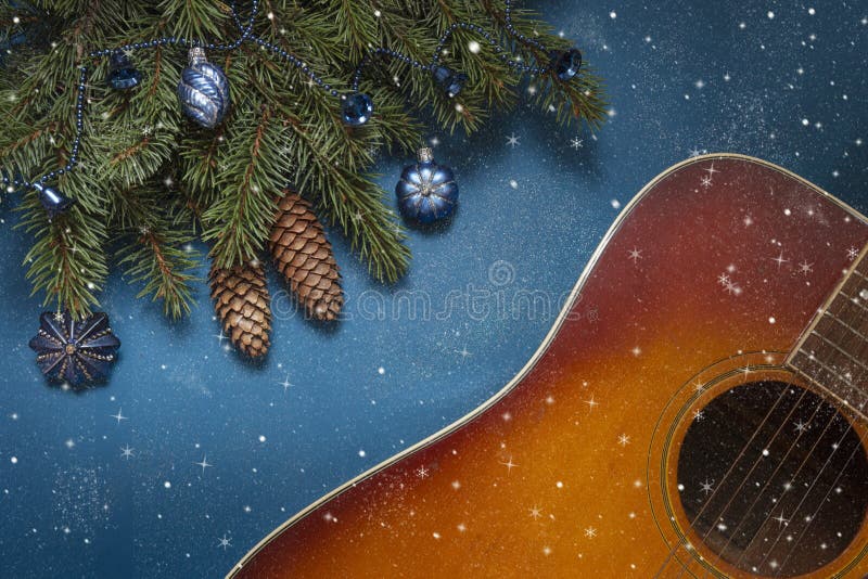 De akoestische gitaar en Kerstmisboomtakken dekorative met blauwe ballen op blauwe achtergrond met opvallende