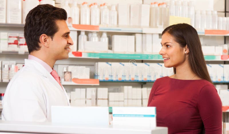 Pharmacist men in a white robe in the pharmacy communicates with the visitor. Pharmacist men in a white robe in the pharmacy communicates with the visitor