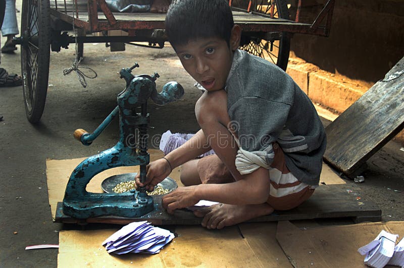 An Indian child labour is working in with a small hand machine on the road just in front of a small scale factory. Due to shortage of space inside he canâ€™t accommodate himself inside the factory. An Indian child labour is working in with a small hand machine on the road just in front of a small scale factory. Due to shortage of space inside he canâ€™t accommodate himself inside the factory.