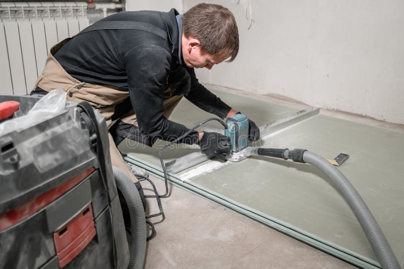 De arbeider gebruikt een de bouwhulpmiddel, de malenhulpmiddelen en een stofzuiger drywall bij negentig graden stock afbeelding De arbeider gebruikt een de bouwhulpmiddel, de malenhulpmiddelen en een stofzuiger drywall bij negentig graden stock afbeelding