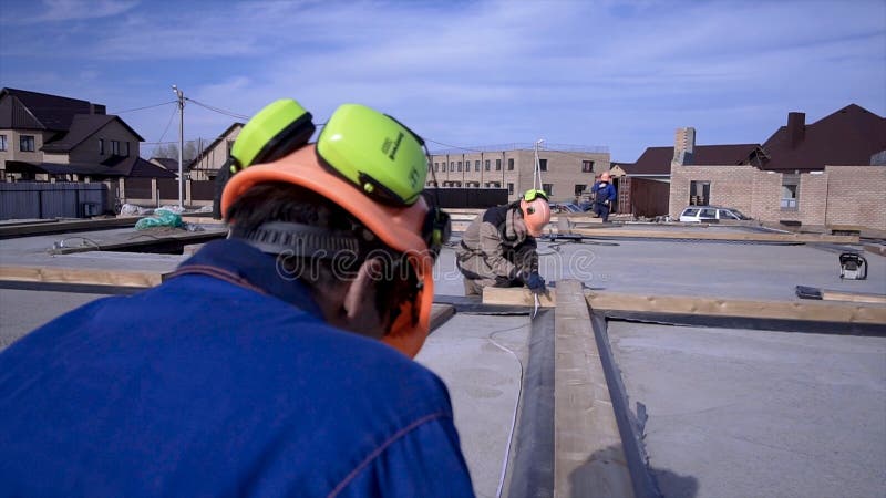 De arbeiders maken metingen metend band bij de bouw klem Bouwers die in eenvormig en bouwvakker bij de bouw werken royalty-vrije stock afbeelding De arbeiders maken metingen metend band bij de bouw klem Bouwers die in eenvormig en bouwvakker bij de bouw werken royalty-vrije stock afbeelding