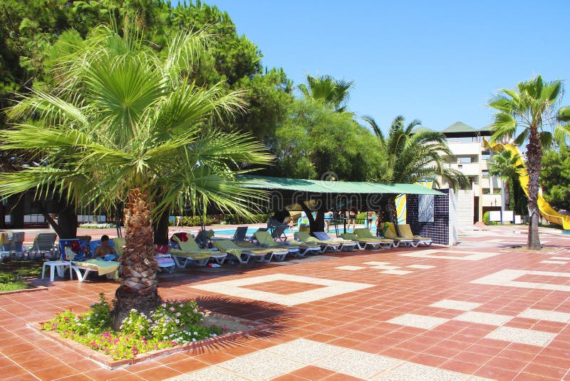 De architectuur van het Turkse hotel met zonlanterfanters, palmen en mensen die in de zomer ontspannen royalty-vrije stock foto's De architectuur van het Turkse hotel met zonlanterfanters, palmen en mensen die in de zomer ontspannen royalty-vrije stock foto's