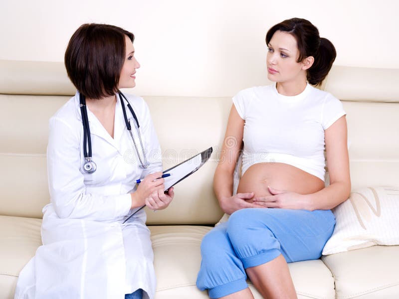 Doctor communicates with pregnant woman - indoors. Doctor communicates with pregnant woman - indoors