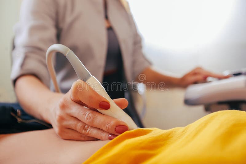De arts maakt de geduldige vrouwen tot buikultrasone klank Ultrasone klankscanner in de handen van een arts royalty-vrije stock foto's De arts maakt de geduldige vrouwen tot buikultrasone klank Ultrasone klankscanner in de handen van een arts royalty-vrije stock foto's