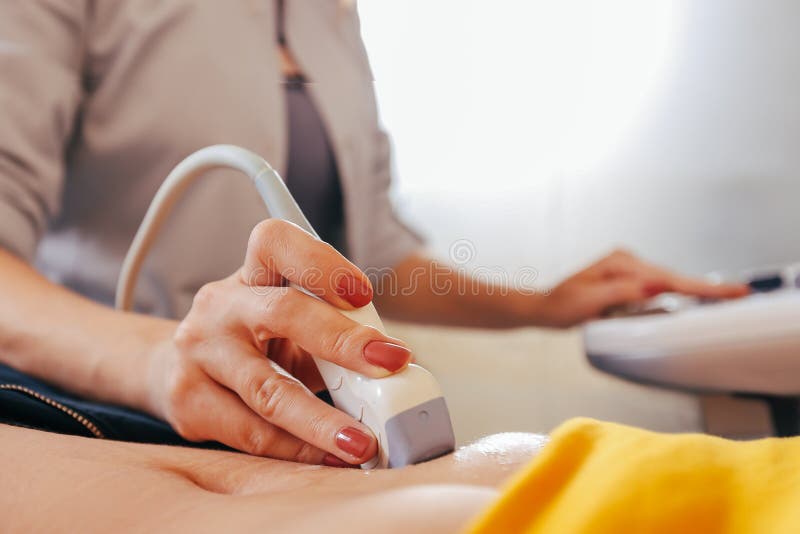 De arts maakt de geduldige vrouwen tot buikultrasone klank Ultrasone klankscanner in de handen van een arts royalty-vrije stock afbeelding De arts maakt de geduldige vrouwen tot buikultrasone klank Ultrasone klankscanner in de handen van een arts royalty-vrije stock afbeelding
