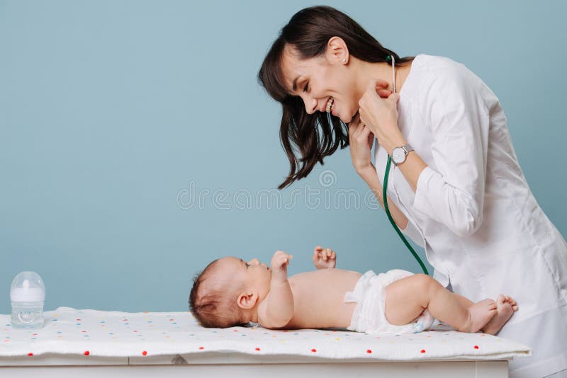 The baby is lying on the table and the pediatrician doctor communicates and plays with him. The baby is lying on the table and the pediatrician doctor communicates and plays with him