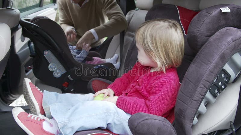 De Autozetels van vaderputting children into