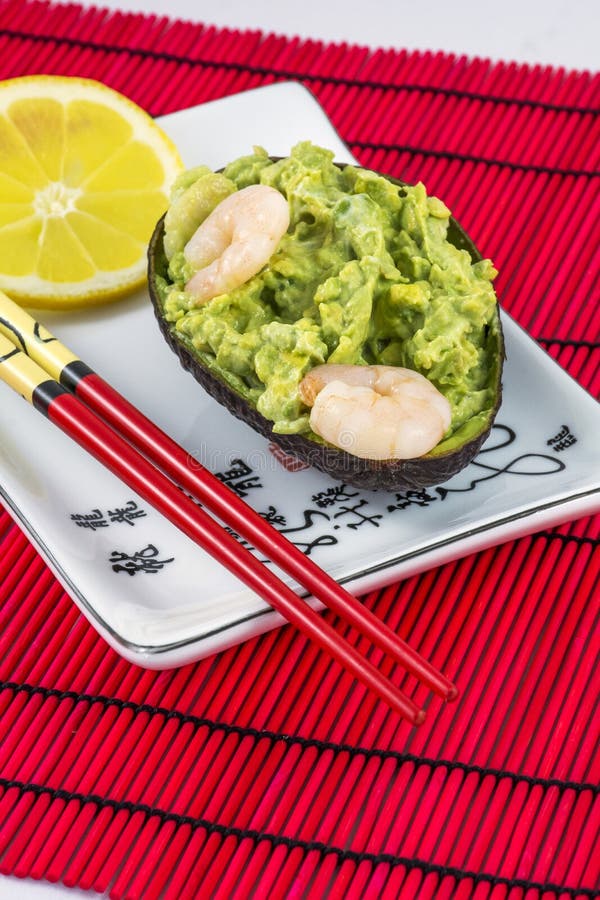 De avocadosalade met garnalen, citroen en eetstokjes ligt op de witte plaat royalty-vrije stock fotografie De avocadosalade met garnalen, citroen en eetstokjes ligt op de witte plaat royalty-vrije stock fotografie