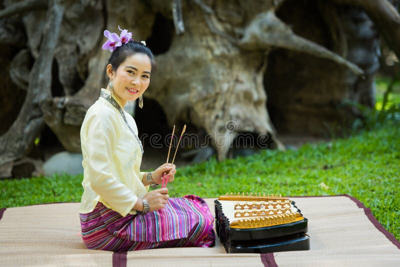 De Aziatische dame met glimlach in Thaise traditioneel wil zich kleden zit en pl
