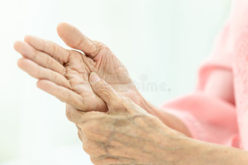 De Aziatische hogere vrouw masseert haar eigen hand, Bejaarde die aan pijn ter beschikking lijden, artritis, beriberi