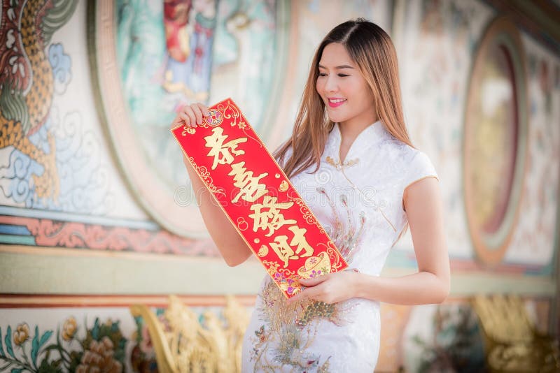 De Aziatische vrouw in het Chinese 'Winstgevende' couplet van de kledingsholding (C stock fotografie De Aziatische vrouw in het Chinese 'Winstgevende' couplet van de kledingsholding (C stock fotografie