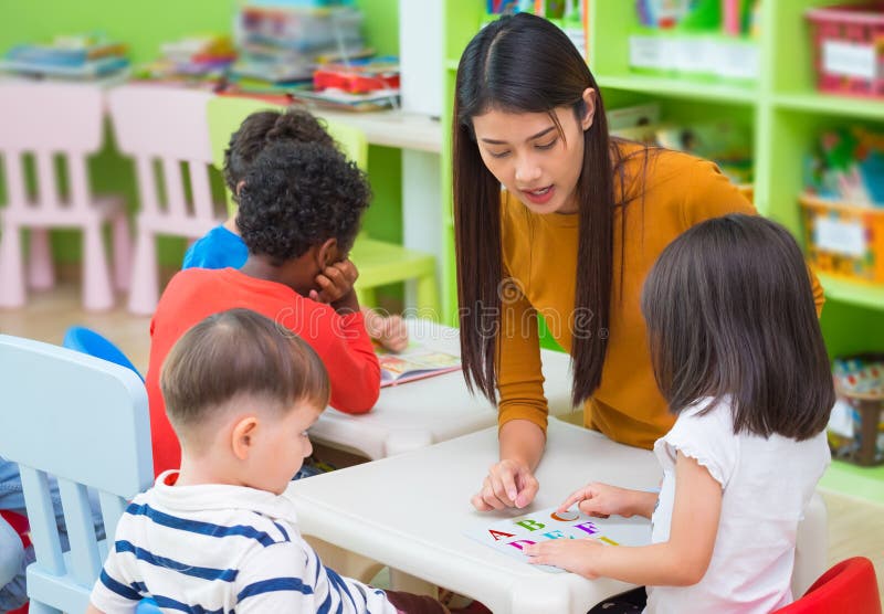 De Aziatische vrouwelijke jonge geitjes die van het leraars het onderwijs gemengde ras boek in cl lezen royalty-vrije stock foto's De Aziatische vrouwelijke jonge geitjes die van het leraars het onderwijs gemengde ras boek in cl lezen royalty-vrije stock foto's