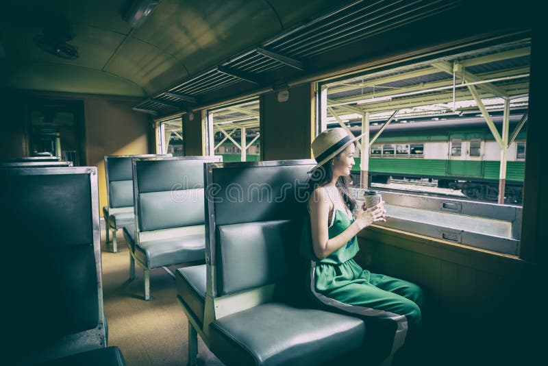 De Aziatische vrouwenreiziger heeft het drinken koffie in de trein met geluk bij Hua Lamphong-post in Bangkok, Thailand royalty-vrije stock fotografie De Aziatische vrouwenreiziger heeft het drinken koffie in de trein met geluk bij Hua Lamphong-post in Bangkok, Thailand royalty-vrije stock fotografie