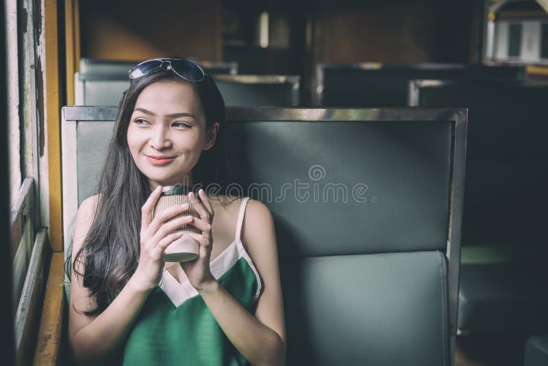 De Aziatische vrouwenreiziger heeft het drinken koffie in de trein met geluk bij Hua Lamphong-post in Bangkok, Thailand royalty-vrije stock foto De Aziatische vrouwenreiziger heeft het drinken koffie in de trein met geluk bij Hua Lamphong-post in Bangkok, Thailand royalty-vrije stock foto