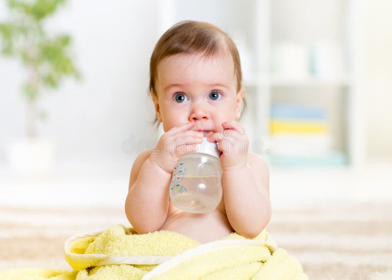 De baby drinkt water van flessenzitting met handdoek stock foto De baby drinkt water van flessenzitting met handdoek stock foto