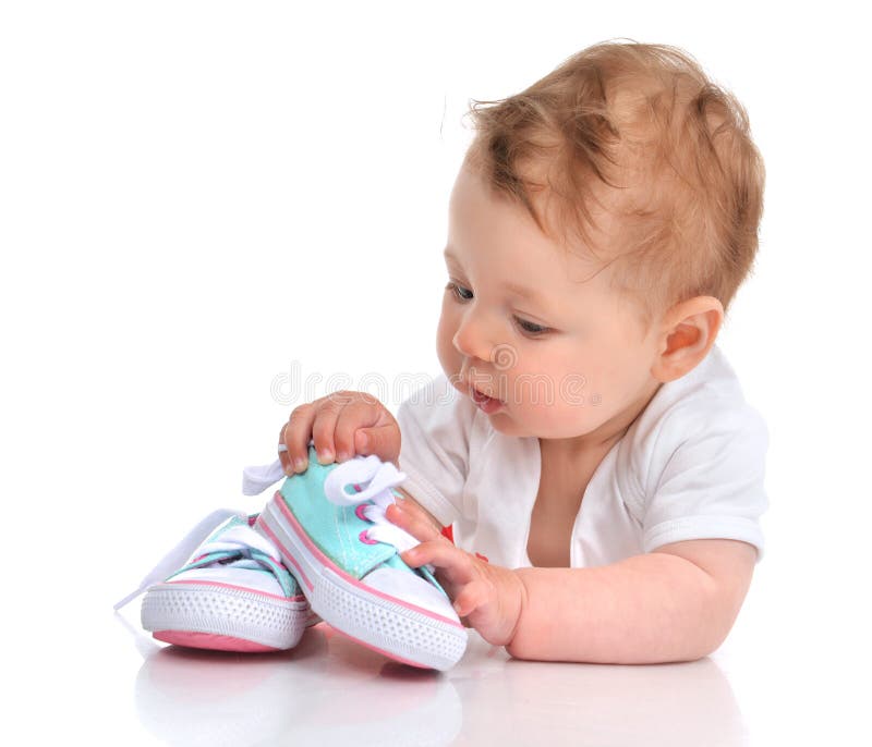 De babymeisje van het zuigelingskind het liggen gelukkige zoekende nieuwe geïsoleerde schoenen