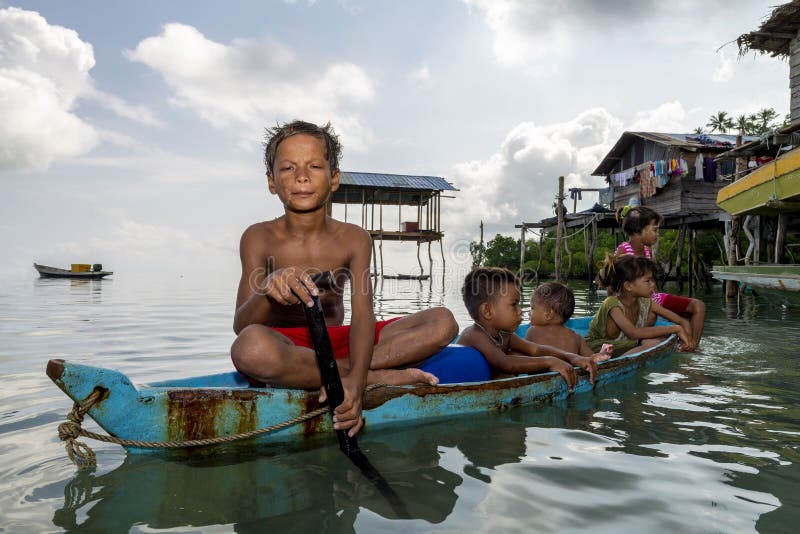 De Bajaukinderen ontspannen op een uitgegraven boot dichtbij oever in Sabah, Maleisië royalty-vrije stock afbeeldingen De Bajaukinderen ontspannen op een uitgegraven boot dichtbij oever in Sabah, Maleisië royalty-vrije stock afbeeldingen