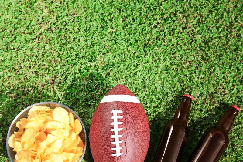 De bal voor Amerikaanse voetbal, drank en spaanders op vers groen vlak gebiedsgras, legt royalty-vrije stock afbeeldingen De bal voor Amerikaanse voetbal, drank en spaanders op vers groen vlak gebiedsgras, legt royalty-vrije stock afbeeldingen