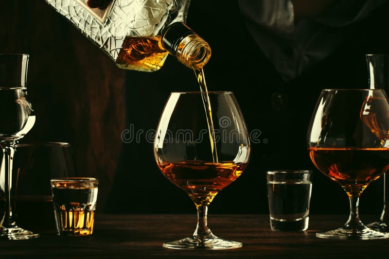 De barman giet de cognac of de brandewijn in groot wijnglas op de oude barteller Uitstekende houten achtergrond in bar of bar, na royalty-vrije stock foto's De barman giet de cognac of de brandewijn in groot wijnglas op de oude barteller Uitstekende houten achtergrond in bar of bar, na royalty-vrije stock foto's