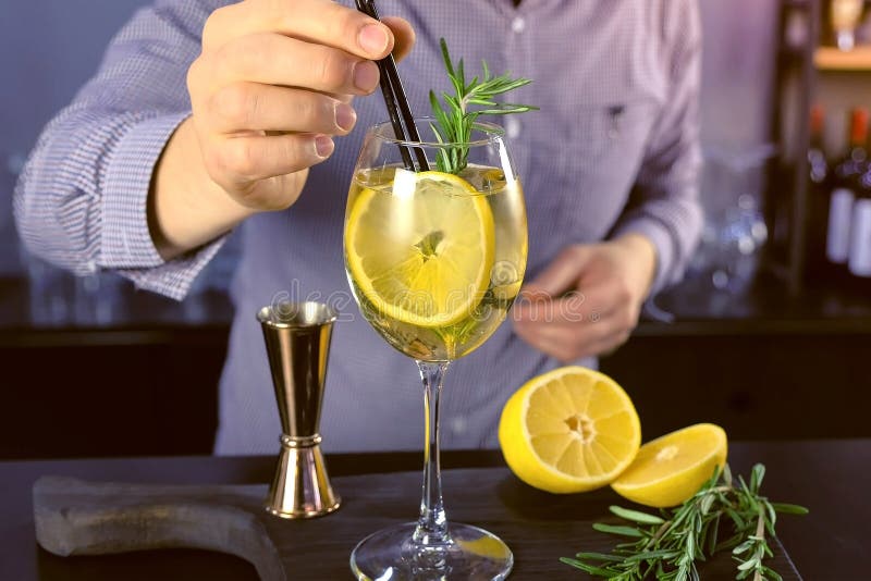De barman zet stro in alcoholcocktail met mousserende wijn, ijs en alcoholische drank in wijnglas, close-upmening stock afbeelding De barman zet stro in alcoholcocktail met mousserende wijn, ijs en alcoholische drank in wijnglas, close-upmening stock afbeelding