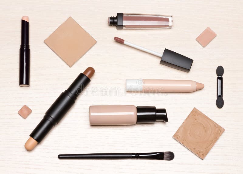 De basismake-upcosmetischee producten op lichte houten lijstvlakte lagen stock afbeeldingen De basismake-upcosmetischee producten op lichte houten lijstvlakte lagen stock afbeeldingen