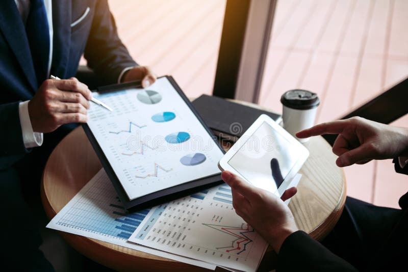 Business partnership coworkers using a tablet to chart company financial statements report and profits work progress and planning in office room. Business partnership coworkers using a tablet to chart company financial statements report and profits work progress and planning in office room.