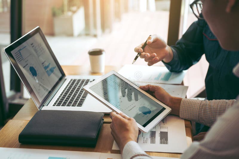 Business partnership coworkers using a tablet to chart company financial statements report and profits work progress and planning in office room. Business partnership coworkers using a tablet to chart company financial statements report and profits work progress and planning in office room.