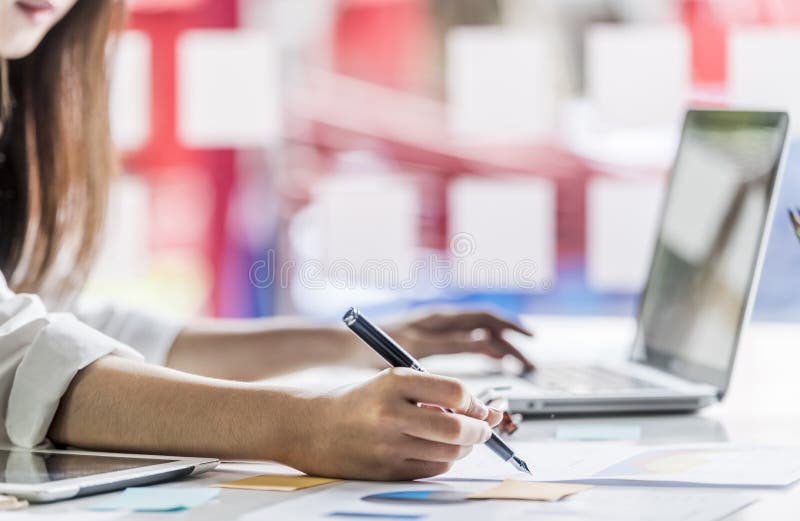 De bedrijfsvrouwen die laptop met behulp van en nemen nota van sommige gegevens stock afbeeldingen De bedrijfsvrouwen die laptop met behulp van en nemen nota van sommige gegevens stock afbeeldingen