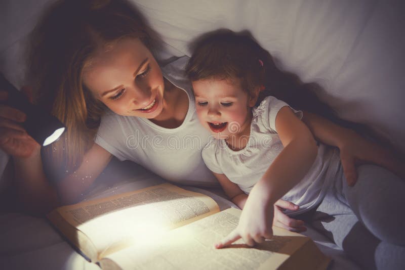 De bedtijd van de familielezing Mamma en kindlezingsboek met een flashl