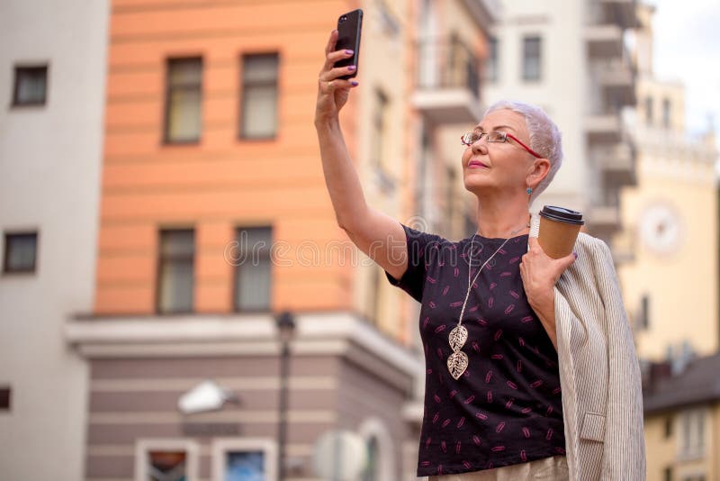 De bejaarde mooie vrouw is in de buitenlandse stad en daar het nemen van foto's aangekomen royalty-vrije stock afbeeldingen De bejaarde mooie vrouw is in de buitenlandse stad en daar het nemen van foto's aangekomen royalty-vrije stock afbeeldingen