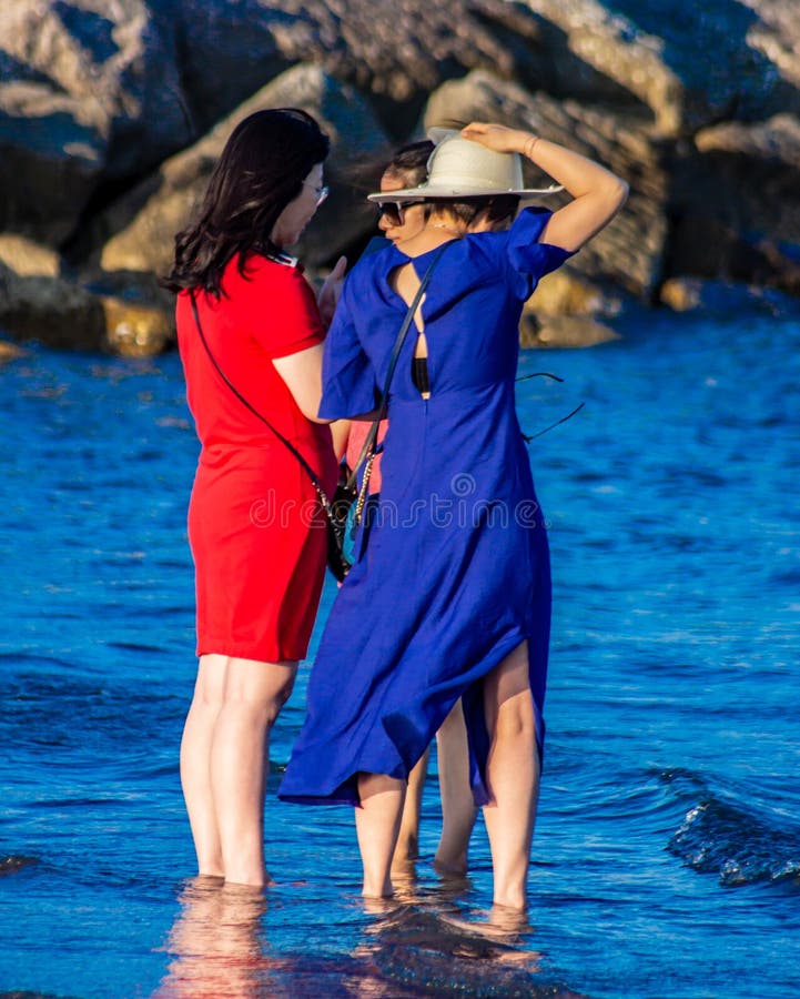 De belles femmes orientales bavardent les pieds dans l'eau avec des vêtements colorés. nous sommes ici à Sottomarina C photos libres de droits De belles femmes orientales bavardent les pieds dans l'eau avec des vêtements colorés. nous sommes ici à Sottomarina C photos libres de droits