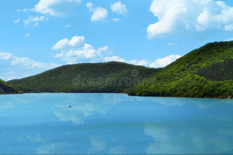 De bergen met groen bos op een meerkust op de hemel met wolkenachtergrond, wolken denken in water na stock afbeeldingen De bergen met groen bos op een meerkust op de hemel met wolkenachtergrond, wolken denken in water na stock afbeeldingen