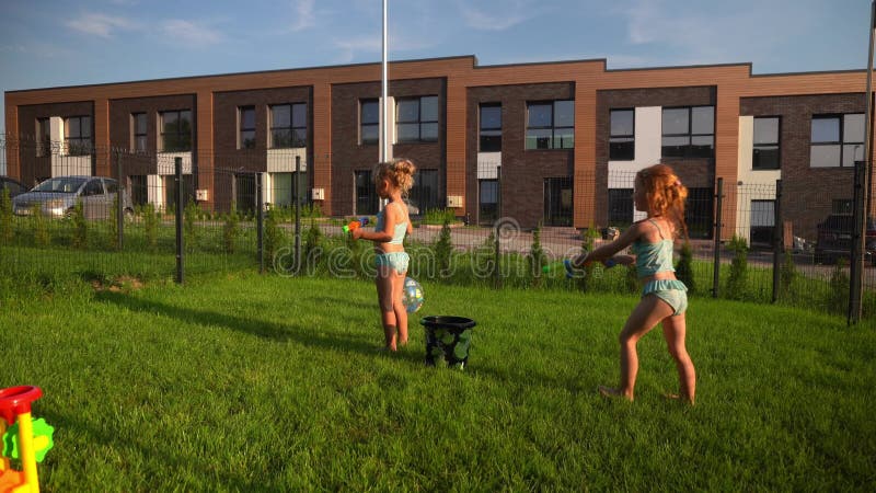 De beste vrienden van de speelmeiden spetteren met waterpistool in de tuin Actieve kinderen