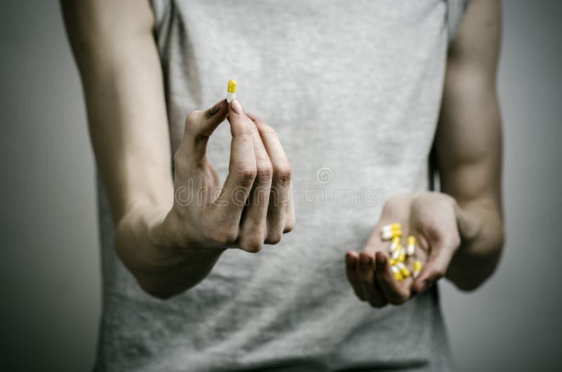 De bestrijding van drugs en drugsverslavingonderwerp: verslaafde die verdovende pillen op een donkere achtergrond houden royalty-vrije stock afbeelding De bestrijding van drugs en drugsverslavingonderwerp: verslaafde die verdovende pillen op een donkere achtergrond houden royalty-vrije stock afbeelding