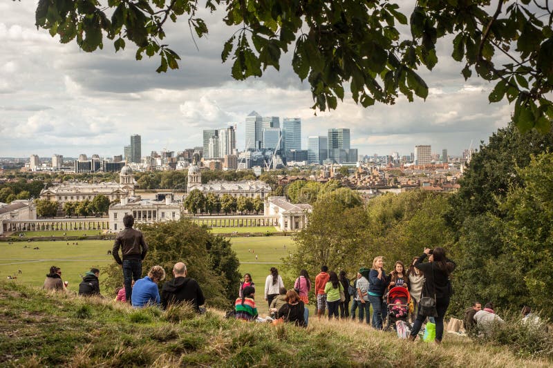 De bezoekers genieten van de mening van de Canary Wharf-wolkenkrabbers van het park van Greenwich in Londen stock afbeelding De bezoekers genieten van de mening van de Canary Wharf-wolkenkrabbers van het park van Greenwich in Londen stock afbeelding
