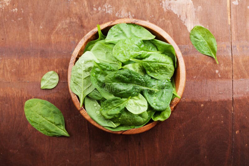 De bladeren van de babyspinazie in houten kom op oude rustieke lijst, natuurvoeding, hoogste mening stock afbeelding De bladeren van de babyspinazie in houten kom op oude rustieke lijst, natuurvoeding, hoogste mening stock afbeelding