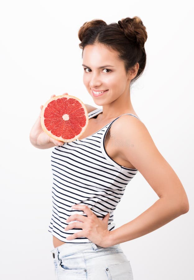 De blije jonge vrouw toont een grapefruit aan Gezonde, natuurlijke foof stock foto De blije jonge vrouw toont een grapefruit aan Gezonde, natuurlijke foof stock foto