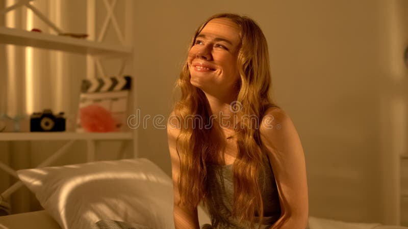 De blije mooie vrouwenzitting op is en het glimlachen, denkend over droom, geluk stock foto's De blije mooie vrouwenzitting op is en het glimlachen, denkend over droom, geluk stock foto's