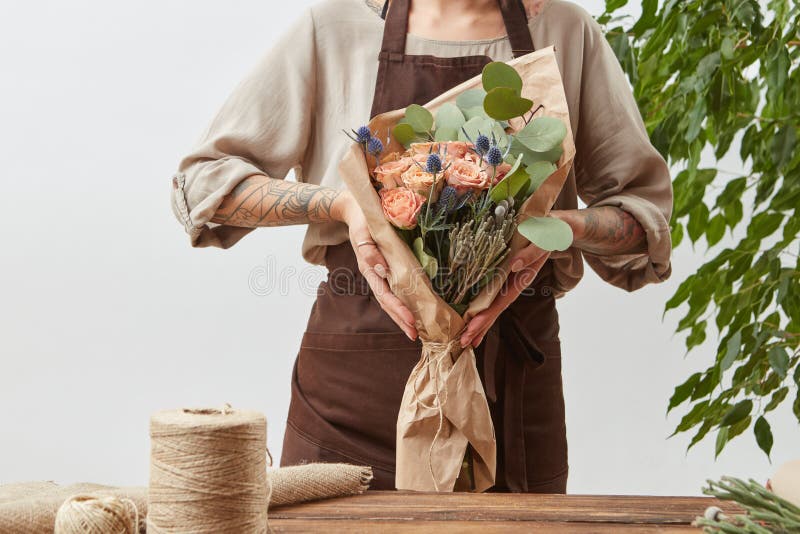 De de bloemisthanden van het meisje houden vers natuurlijk boeket van de geurige bloemen het leven rozen van de koraalkleur, groe stock foto De de bloemisthanden van het meisje houden vers natuurlijk boeket van de geurige bloemen het leven rozen van de koraalkleur, groe stock foto