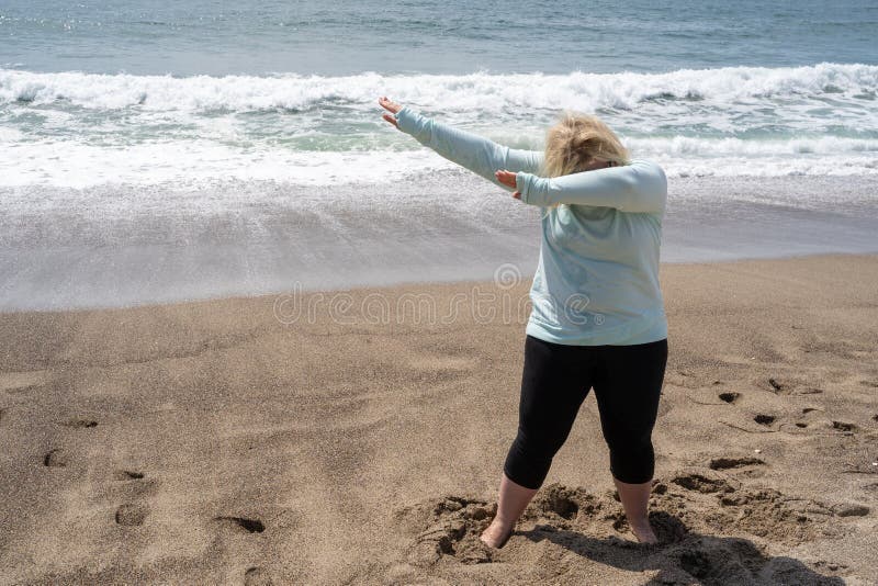 De blondevrouw doet een bettende dansbeweging op het strand stock afbeelding De blondevrouw doet een bettende dansbeweging op het strand stock afbeelding