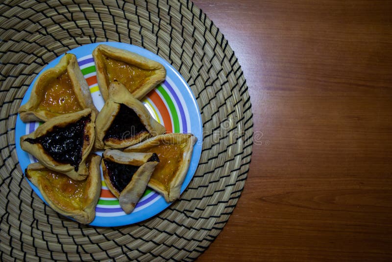 De bosbes en de abrikoos van Hamantashpurim blokkeren koekjes in gekleurde plaat met houten lijstachtergrond stock foto De bosbes en de abrikoos van Hamantashpurim blokkeren koekjes in gekleurde plaat met houten lijstachtergrond stock foto