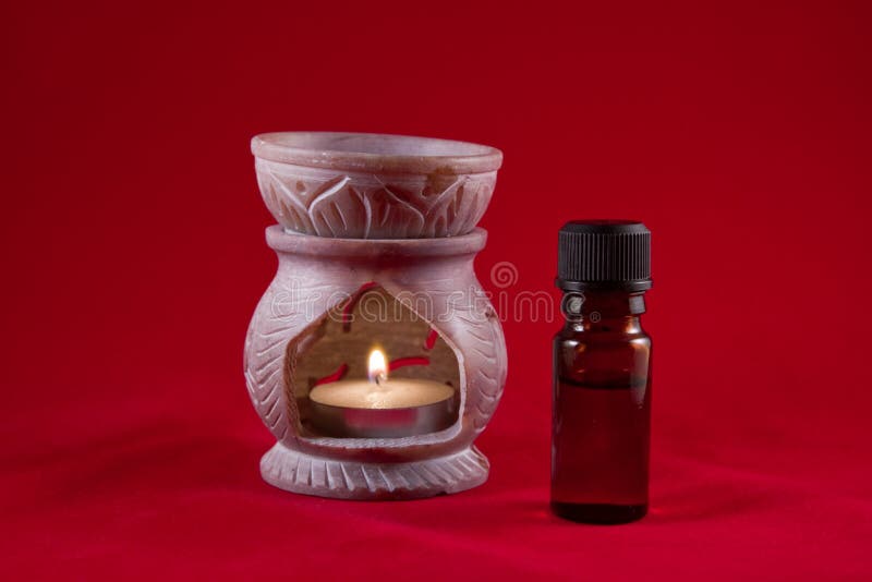 De brander van de olie met fles op rode achtergrond stock fotografie De brander van de olie met fles op rode achtergrond stock fotografie
